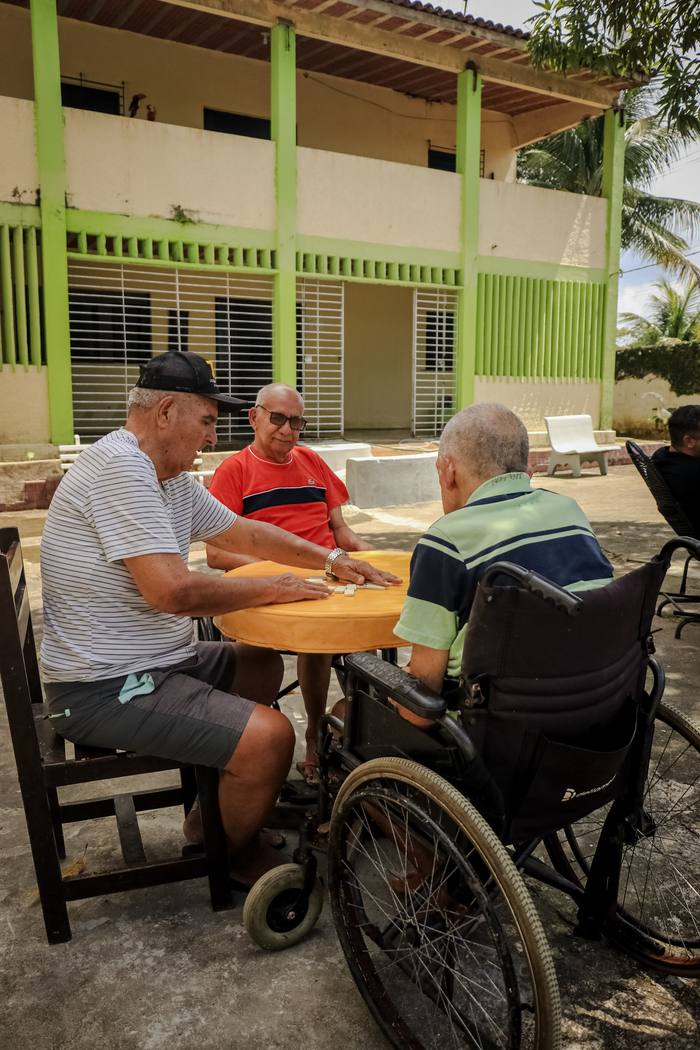 Grupo jogando dominó em frente ao prédio principal